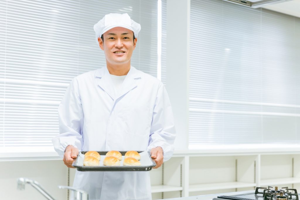 食品成形機で作られた菓子を持つ男性